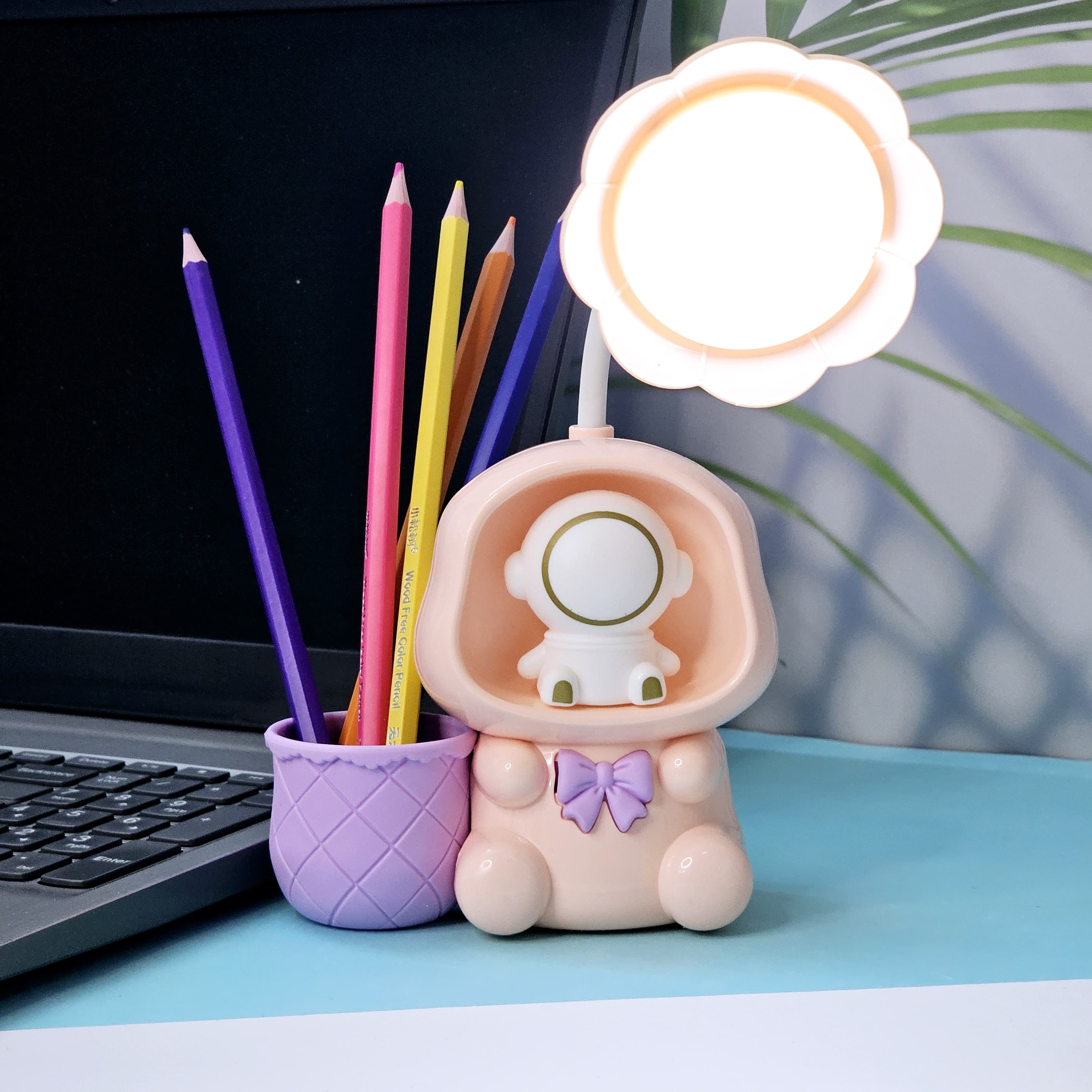 "Usmile Toys multifunctional kids' lamp: a blue, pink, and green astronaut figure with a flower-petal light and an integrated pencil holder, enhancing study time and room decor." www.usmile.toys